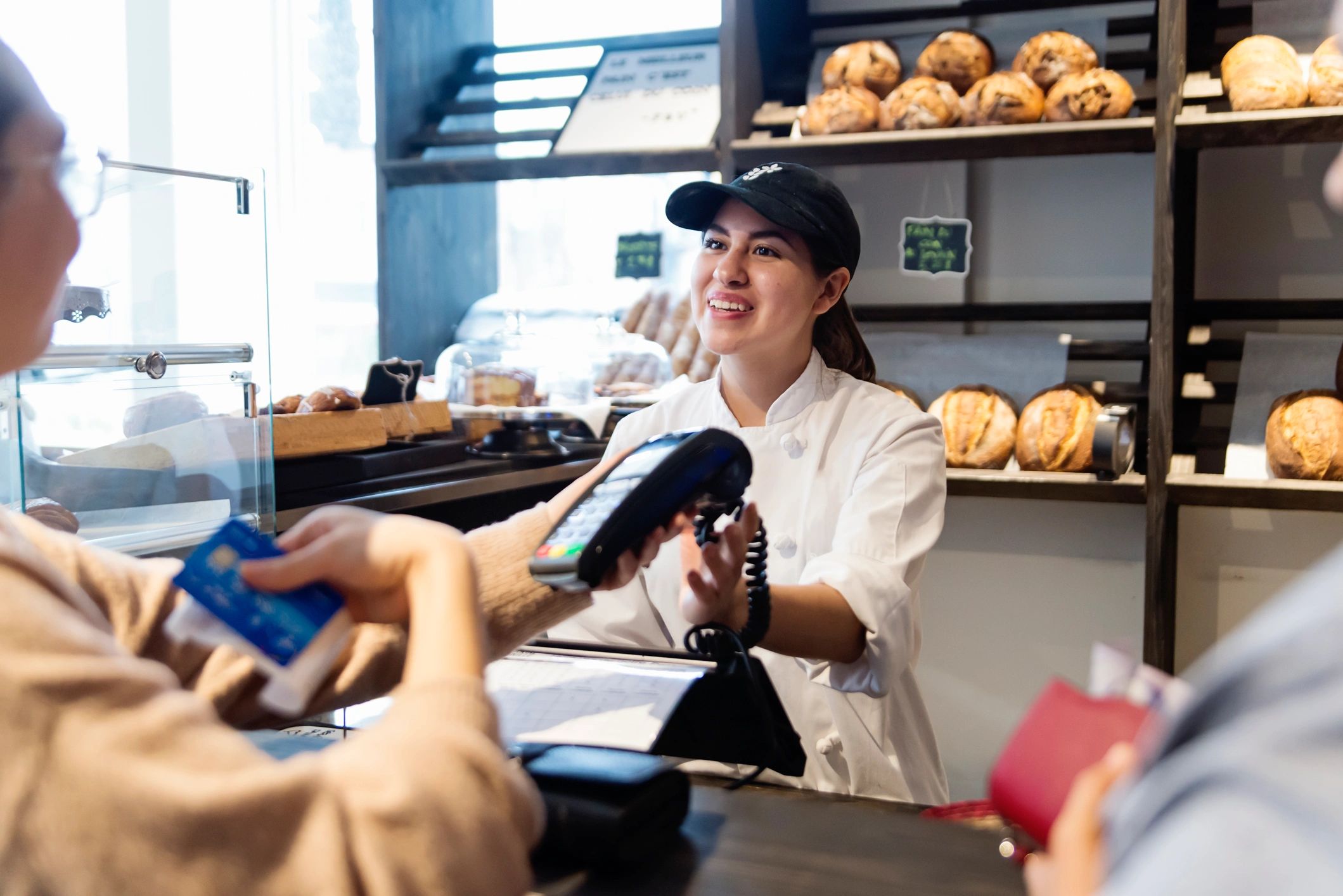 Small bakery owner assisting customers inside a local shop